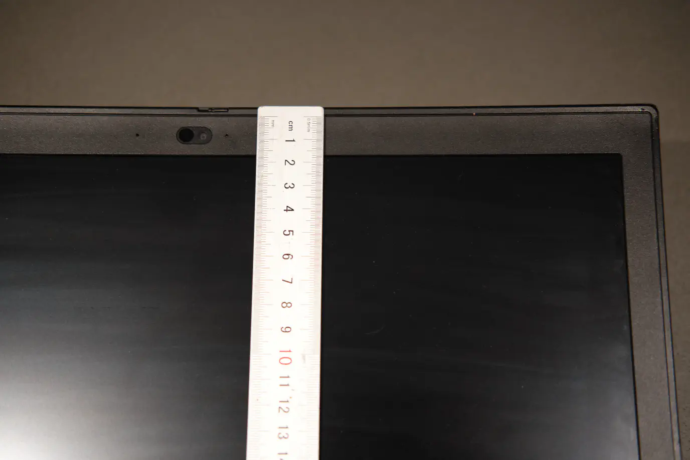 A metric ruler held up to the upper bezel of a ThinkPad P53